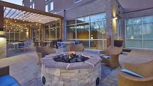 An outdoor patio with a stone fire pit, wicker furniture, and a covered seating area. - SpringHill Suites by Marriott Chattanooga North/Ooltewah (Ooltewah)
