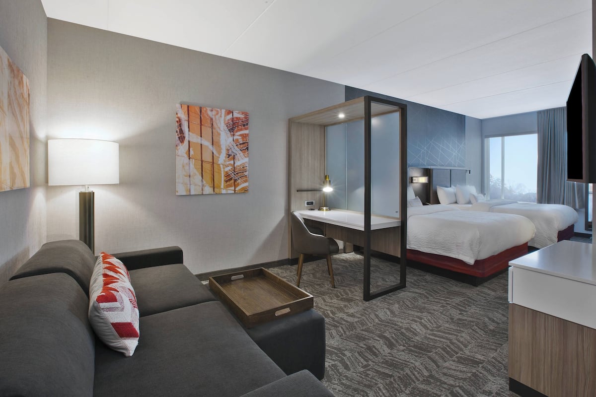 Ein Hotelzimmer mit Sofa, Schreibtisch, Bett und einem großen Fenster.