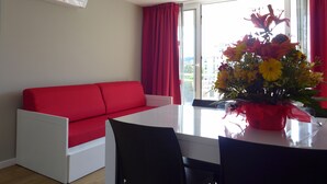 A modern room with a red sofa, a white table, and a vase of flowers. - Rentalmar Navarra (Salou)
