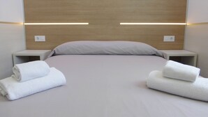 A modern hotel room with a neatly made bed, two bedside tables, and two wall-mounted light fixtures. - Rentalmar Navarra (Salou)