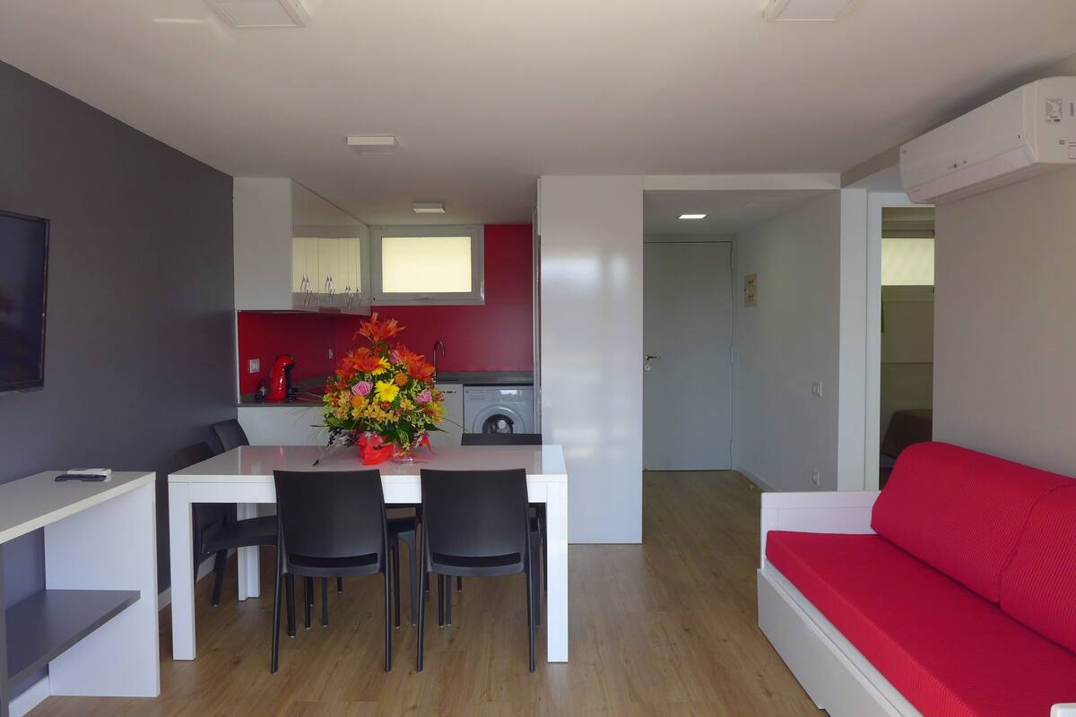 A modern kitchen with white cabinets, a red backsplash, and a dining area with a white table and black chairs.