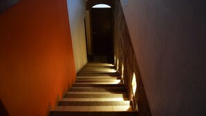 A narrow stairway with alternating light and dark steps, leading to a dark doorway at the end. - Casa Palmas (Guanajuato)