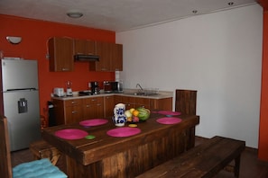 A compact kitchen with wooden cabinets, a refrigerator, a microwave, and a sink.