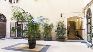 Ein Innenhof mit Blumentöpfen, einer Treppe und einem Hauseingang.