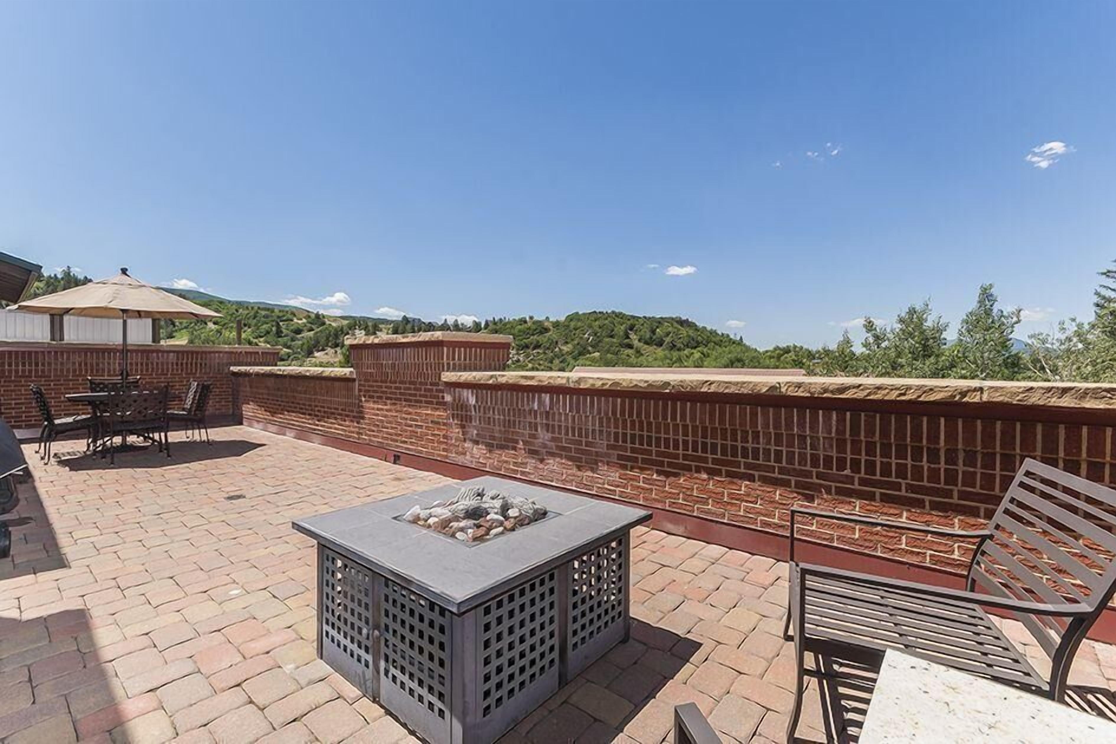 Une terrasse extérieure avec un foyer, des sièges et un mur en briques.