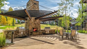 Un patio exterior con chimenea de piedra, zona de parrillada y mobiliario.