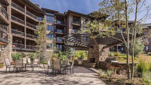 A multi-story building with outdoor seating and a covered patio area. - First Tracks 3301 2 Bedroom Condo by RedAwning (Steamboat Springs)