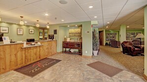 A reception area with a wooden desk, framed pictures on the walls, and a seating area with leather chairs. - Phoenix 118A - 3 Br Condo (Steamboat Springs)