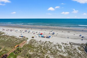 A beach with a wooden boardwalk, sandy beach, and clear blue sky. - Ocean Bay Club 909 by RedAwning (North Myrtle Beach)