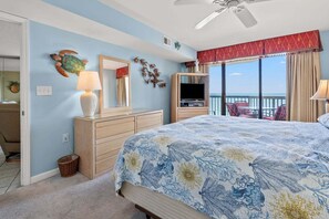 A bedroom with a bed, dresser, mirror, and a view of the ocean. - Ocean Bay Club 909 by RedAwning (North Myrtle Beach)