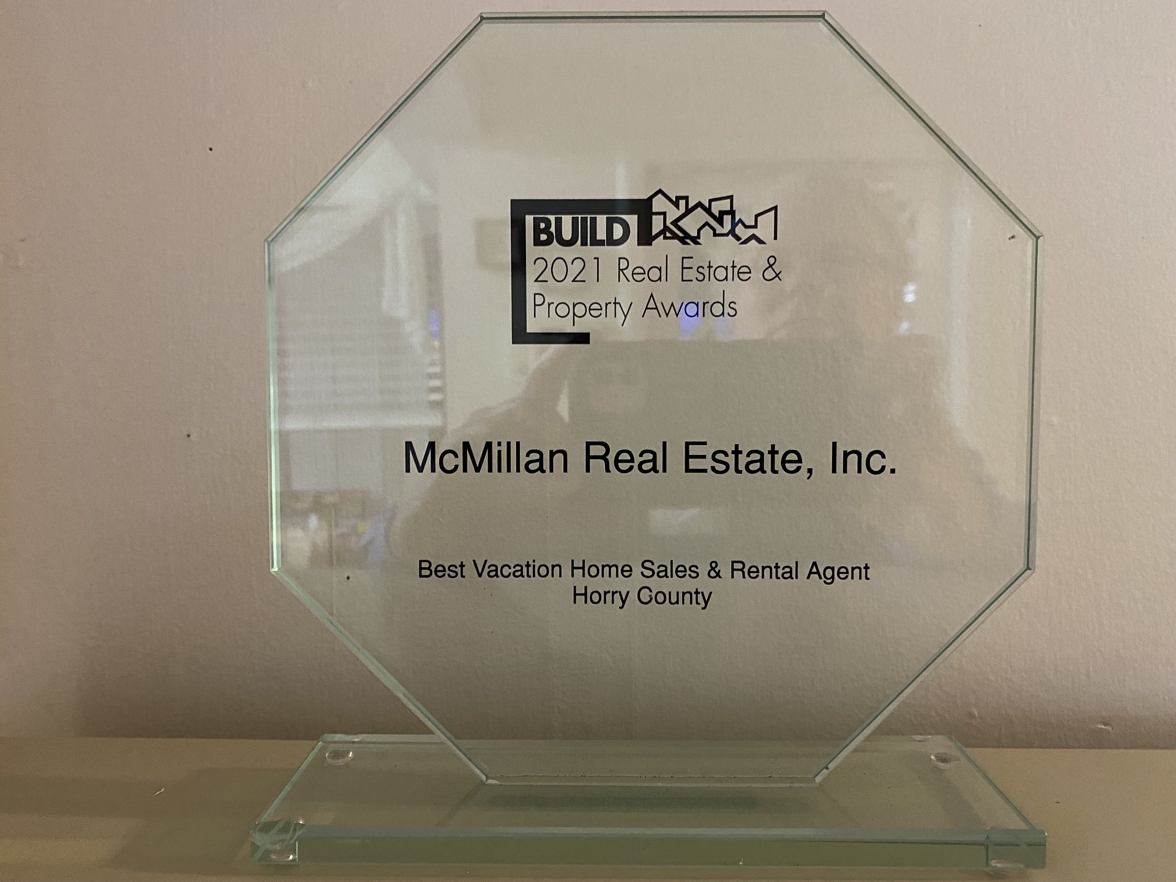 A glass award plaque for McMillan Real Estate, Inc. Best Vacation Home Sales & Rental Agent in Horry County.