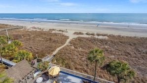 A beach view with a wooden deck, palm trees, and a boardwalk leading to the beach. - Shoreham Towers 5C by RedAwning (North Myrtle Beach)