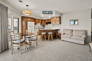 A compact living space with a kitchenette, a dining area with a table and chairs, and a sofa. - Tilghman Lakes B3 by RedAwning (North Myrtle Beach)