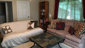 A living room with a ceiling fan, a sofa, a loveseat, a coffee table, and a bookshelf. - Private MIL Apartment in Serene Pacific Northwest Setting (Kenmore)