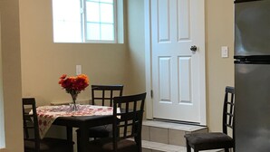 A dining area with a table set for four, a refrigerator, and a door with a window above it. - Private MIL Apartment in Serene Pacific Northwest Setting (Kenmore)