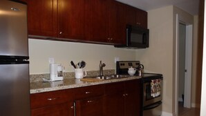 A kitchen with wooden cabinets, a stainless steel refrigerator, a microwave, a coffee maker, and a stove. - Private MIL Apartment in Serene Pacific Northwest Setting (Kenmore)
