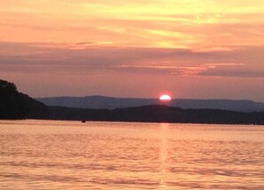 A sunset over a calm body of water with distant hills. - Private Dock + Game Room + Event Space for special occasions. (Georgetown)