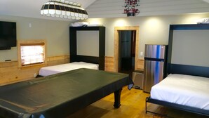 Ein Zimmer mit zwei Betten, einem Tisch, einem Fernseher und einem Kühlschrank.