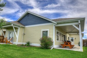 Une maison avec un porche abrité, un petit jardin et un espace salon extérieur.