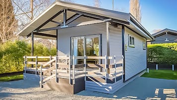 Una casa móvil moderna de un piso, con un porche cubierto y un camino de entrada de grava.