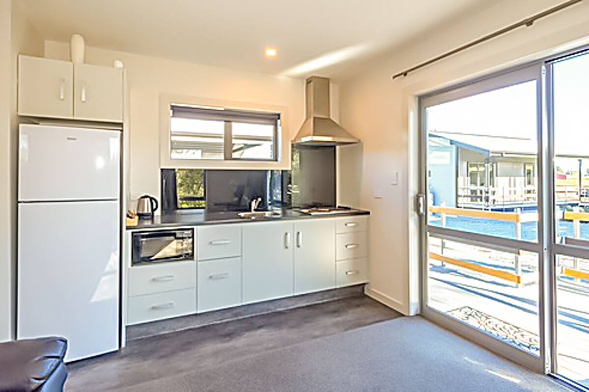A modern kitchen with white cabinets, a built-in oven, and a large window providing a view of the outside.