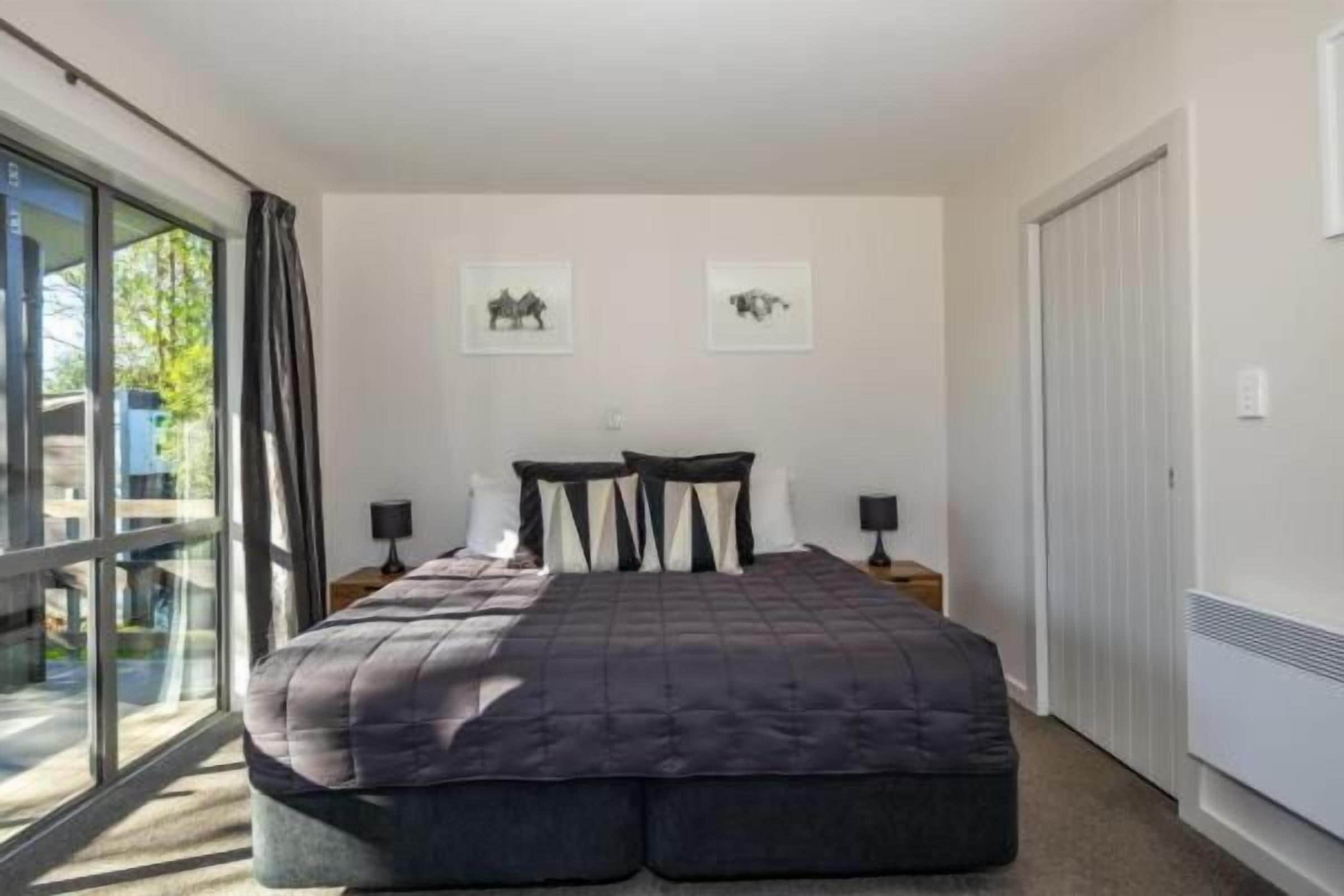 A bedroom with a large bed, two bedside tables, and a sliding glass door to a balcony.