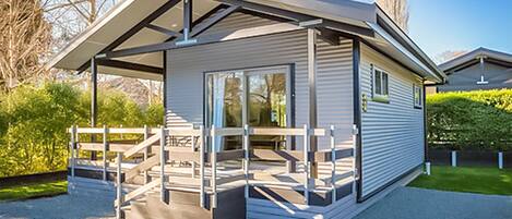 A modern, single-story structure with a covered patio area, large windows, and a gravel driveway.