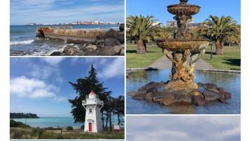 Une promenade en bois menant à une plage, une jetée rocheuse, un phare blanc et une statue dans un parc.