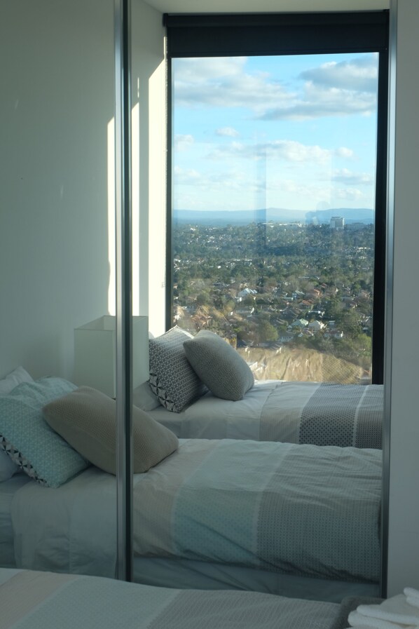 A bedroom with a large window offering a cityscape view.