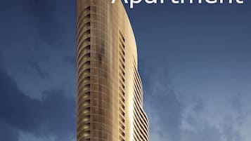 A tall, modern apartment building with a curved facade and multiple balconies.