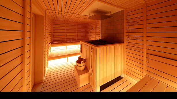 Eine Holzsauna mit Sitzbank, Eimer und Wandheizung.