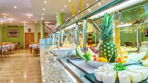 A buffet with various food items including fruits, cheeses, and a pineapple. - Aparthotel Playa Parc (Mercadal)