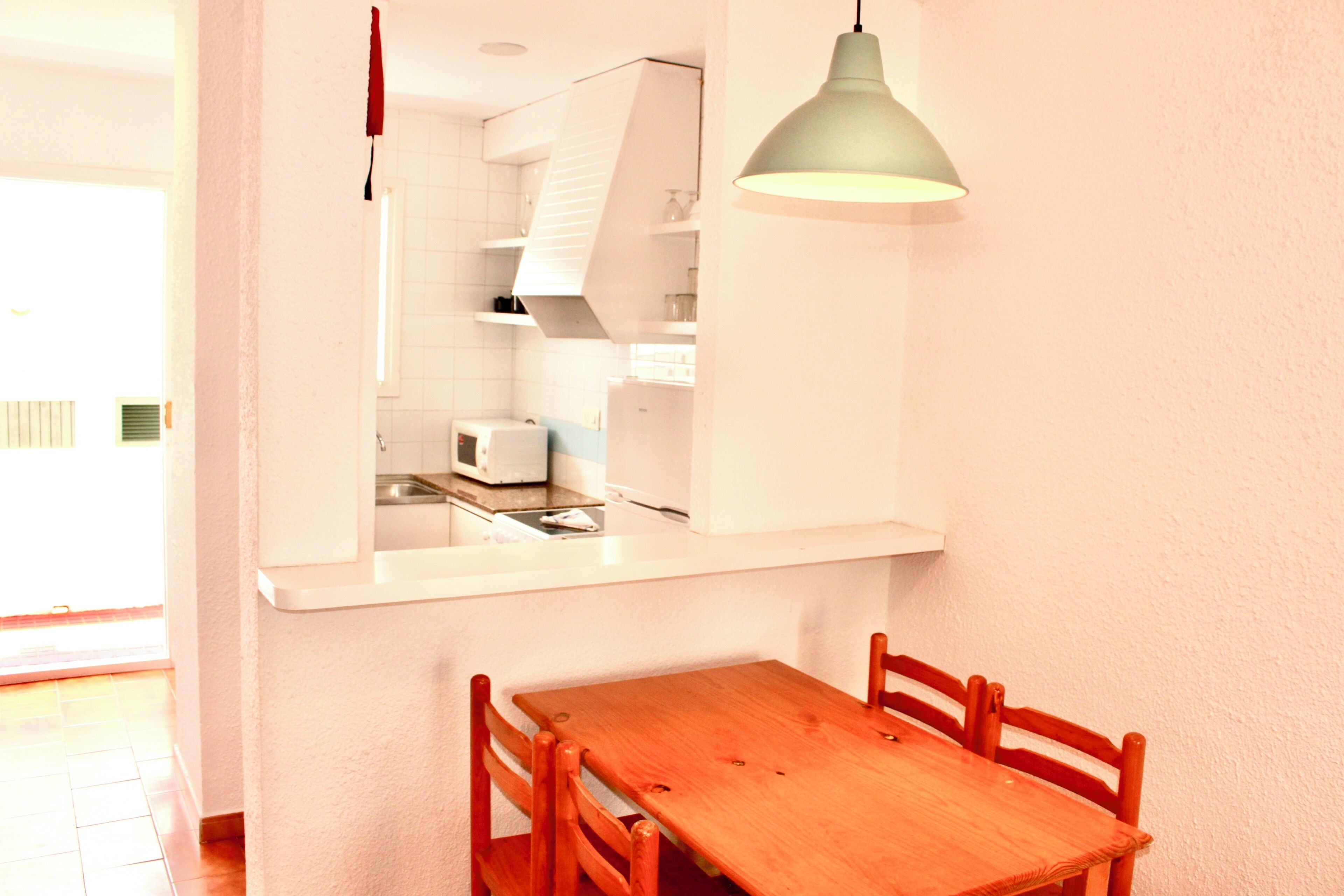 Une cuisine avec des meubles blancs, un four à micro-ondes et une table en bois avec des chaises.