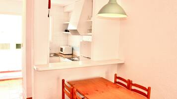 Une cuisine avec des meubles blancs, un four à micro-ondes et une table en bois avec des chaises.