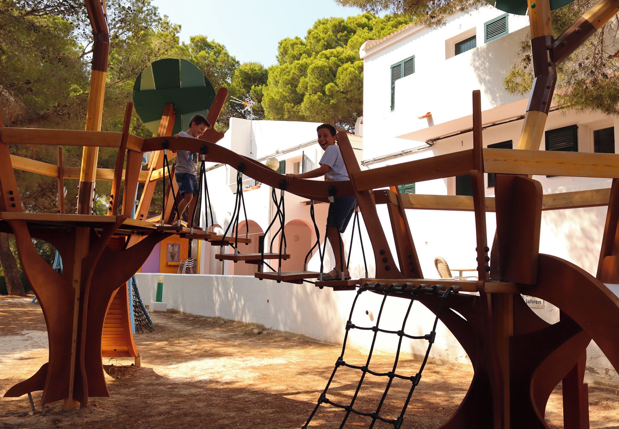 A playground with wooden structures and a netted climbing area.
