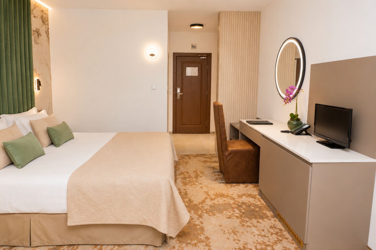 Habitación de hotel con cama, escritorio, computadora, silla, televisor y espejo.