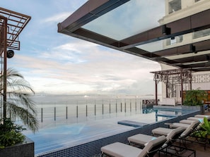 Una piscina infinita con sillones de descanso, vista al mar y diseño arquitectónico moderno.
