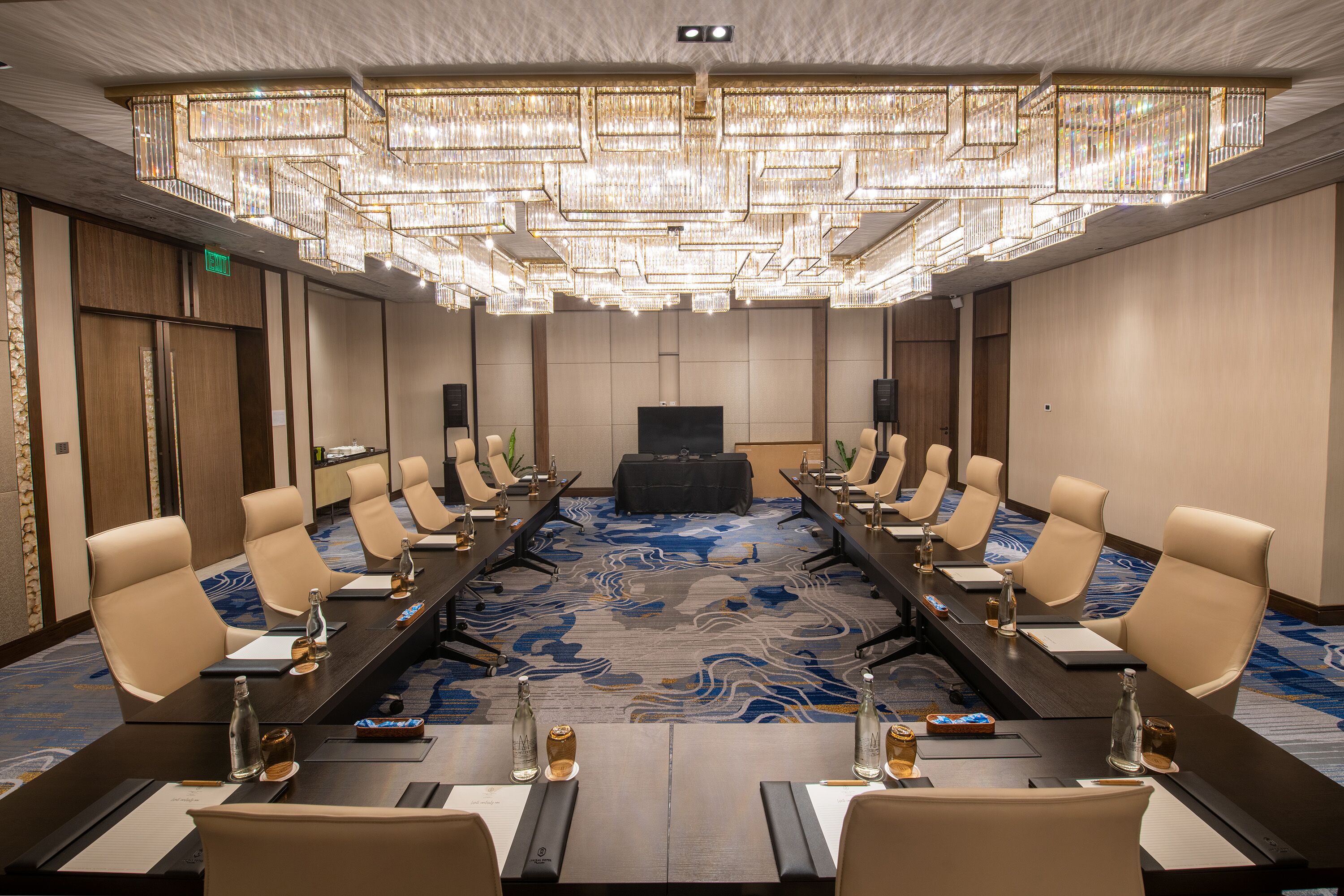 A conference room with a long table, multiple chairs, and a large chandelier.