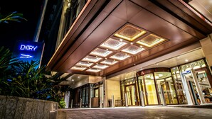 Una entrada de hotel con un llamativo letrero que dice 'ENTRY', fachada de vidrio y un diseño arquitectónico moderno.