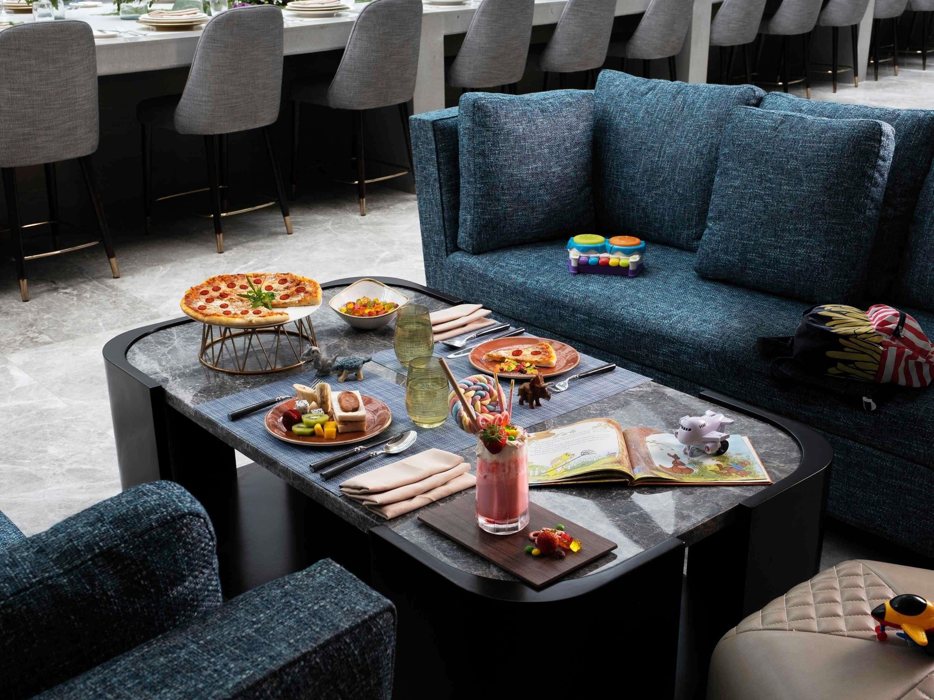 A dining area with a round table set for two, a blue sofa, and a small play area with toys.