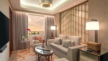 Une chambre d’hôtel moderne avec un canapé, une table basse, un téléviseur et une vue sur l’océan.