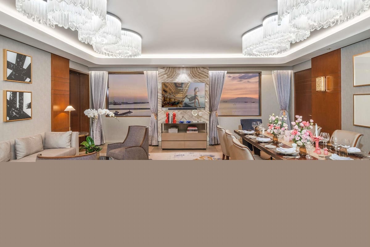 A modern hotel room with a large window, a dining area, and a seating area.