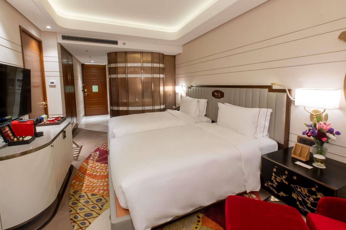 A hotel room with a large bed, a desk with a TV, and a red chair.