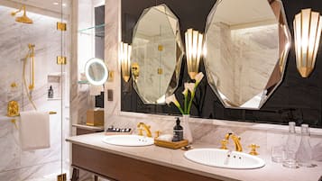 A modern bathroom with two sinks, a large mirror, and a shower.