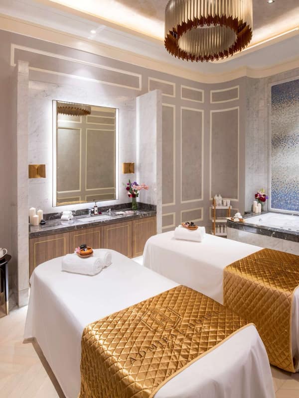 Relax in a serene spa room with a bathtub, two beds, and a cozy armchair.