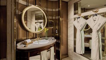 A modern bathroom with a large mirror, a vanity with a sink, and two robes hanging on hooks.