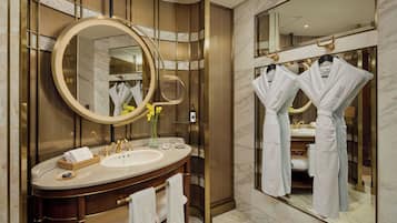 Un baño moderno con un espejo grande, un tocador con lavamanos y dos batas colgadas en ganchos.