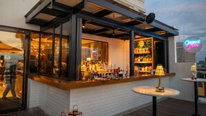 Una zona de bar con pared de ladrillo blanco, ventanas de vidrio y un letrero de neón.