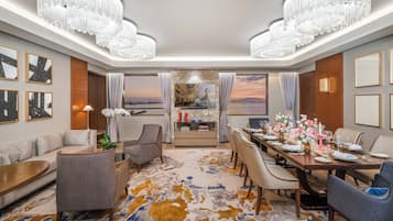 Habitación de hotel con comedor, sofá, mesa de centro y vista al mar.