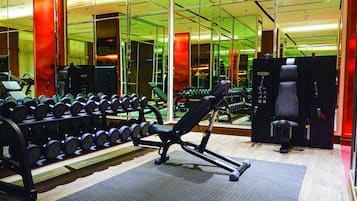 Ein Fitnessstudio mit Trainingsgeräten, Spiegeln und einem gemusterten Boden.